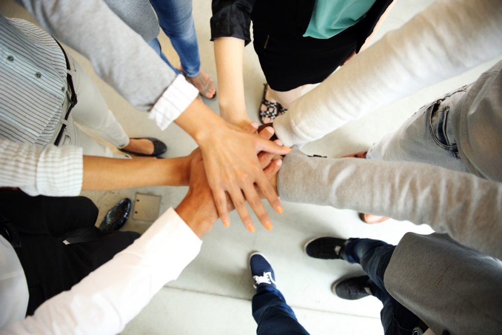 business people joining hands held high 1500 x 300